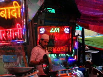 A neon sign spells a biryani shop name at a food stall in Delhi.
