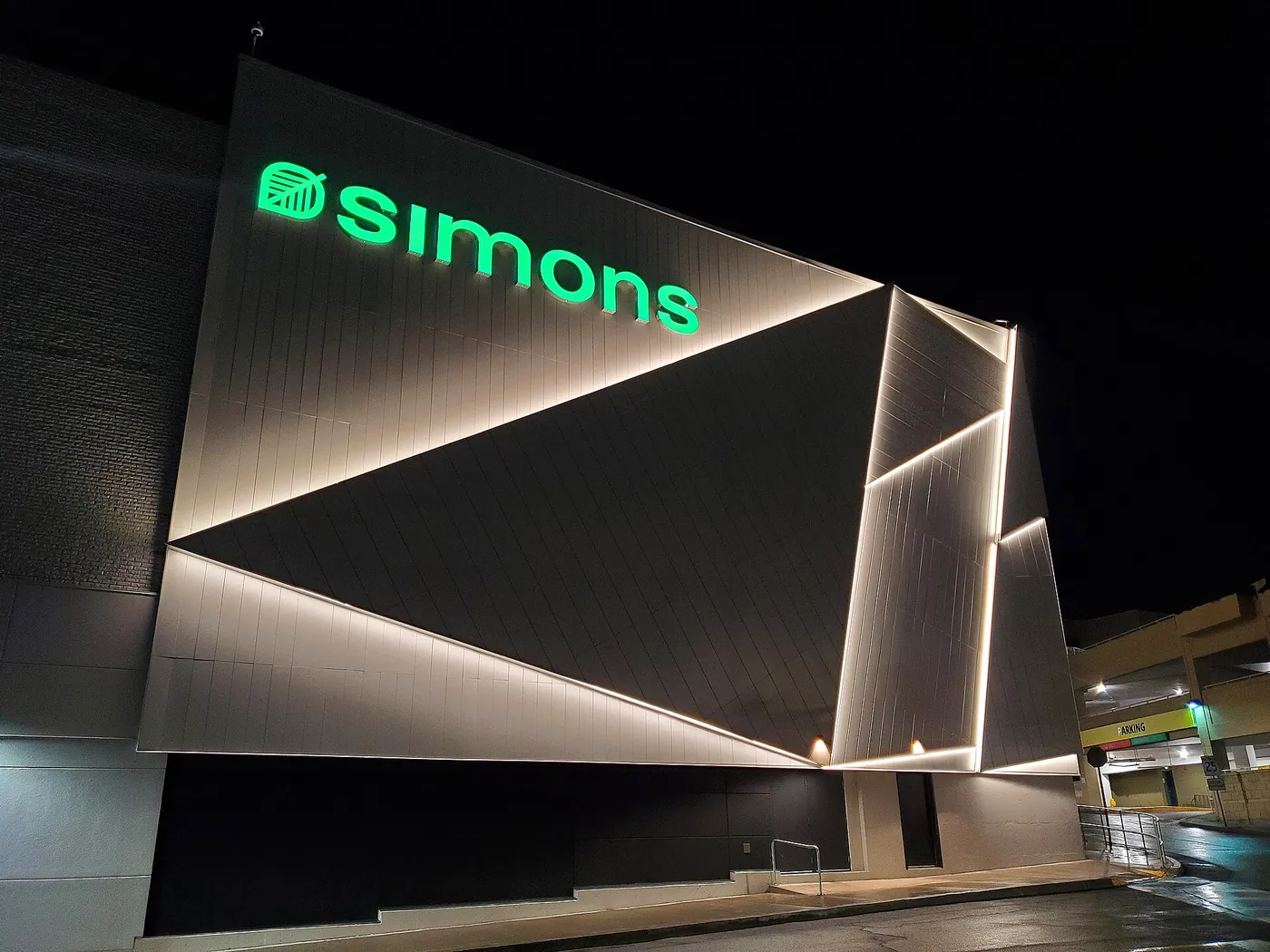 Green illuminated letters name a retail store across a lit shopfront facade.