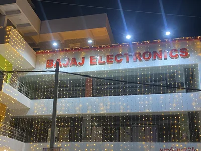 Lit channel letters spell Bajaj Electronics on a shop building in Gadwal at night.