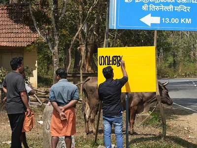 A sign painter in Wayanad works on a board, the closest Indian photograph of sign repair.